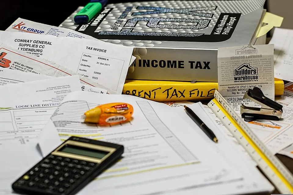 Investisseur immobilier analysant une calculatrice fiscale et des documents d’impôts