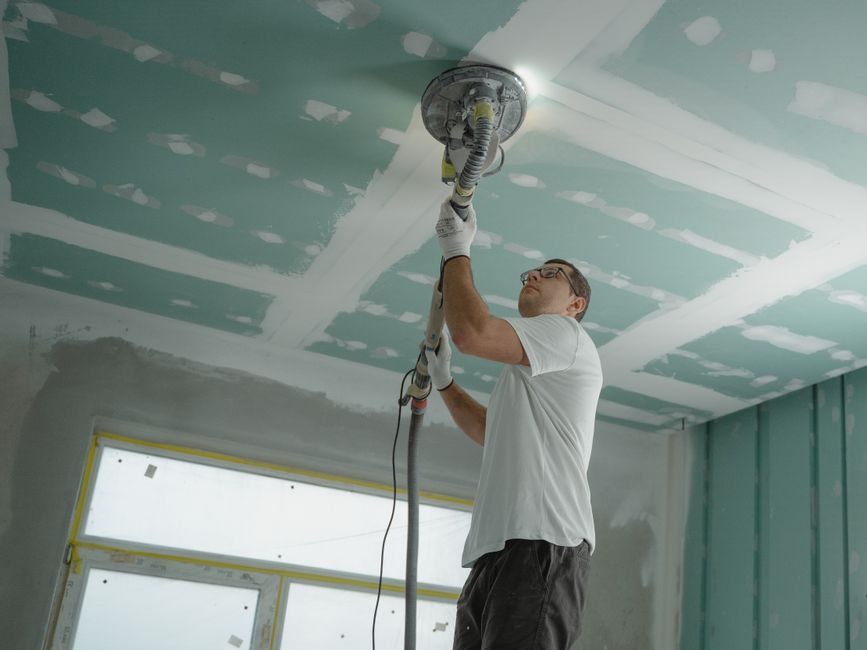 Types d’investisseurs immobiliers : professionnel ponçant un plafond sur un chantier de rénovation